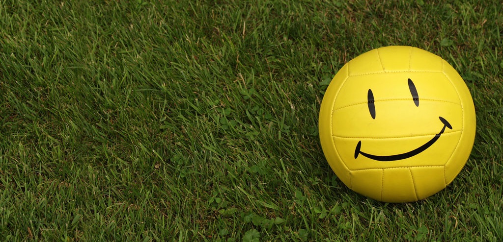 Banner image for testimonials page of a yellow soccer ball that has a smiley face painted on it.